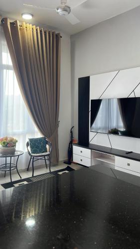 uma sala de estar com uma televisão de ecrã plano e uma cadeira em MV Suite Homestay em Kuantan