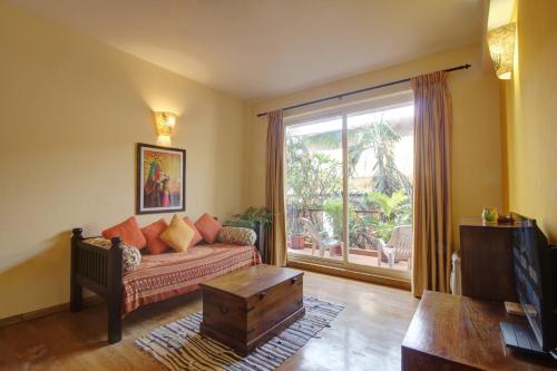Genesis Leisure - Charming home-stays near Anjuna, Vagator & Assagao في أنجونا: غرفة معيشة مع أريكة ونافذة كبيرة