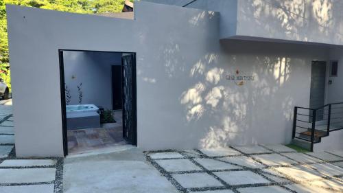 a white building with a black door on the side at CASA MARIPOSA en Punta Leona a 500 metros de la playa FULL EQUIPADA Espacio y precio a tu medida Posibilidad de alquilar la casa entera, los dos apartamentos abajo o los 2 cuartos con baños privados en la planta alta Para 1 a 22 personas in Herradura