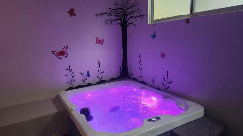 Baño púrpura con bañera con árbol y mariposas en Casa Mariposa en Herradura