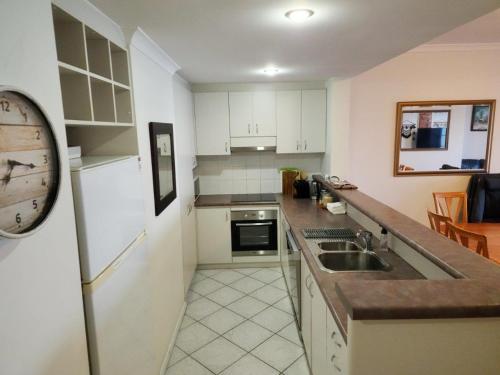 a kitchen with a sink and a clock on the wall at The Boardwalk Apartment in Rockingham