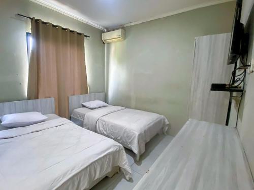 a room with two beds and a television in it at Limo Depok Residence RedPartner in Depok