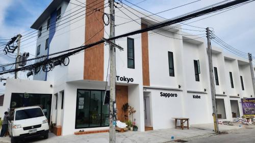 a white building with a truck parked in front of it at Airhub Hostel Phuket Airport in Ban Bo Han