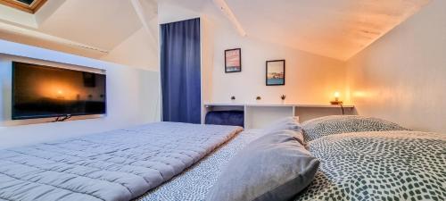 a bedroom with two beds and a flat screen tv at Le Studio de Véra - Intra Muros - Wifi in Avignon