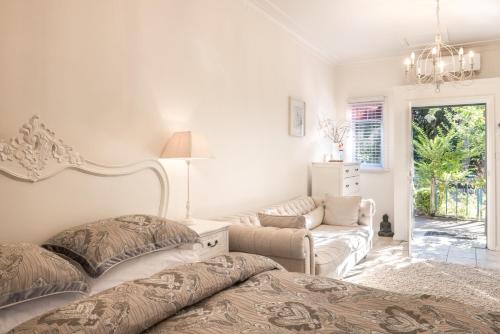 a white bedroom with two beds and a couch at Velvet Pear Cottage in Central Tilba