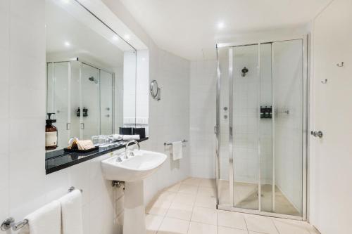 a white bathroom with a sink and a shower at Crowne Plaza Canberra by IHG in Canberra