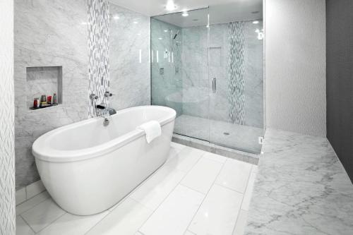 un bagno bianco con vasca e doccia in vetro di Raleigh Marriott Crabtree Valley a Raleigh