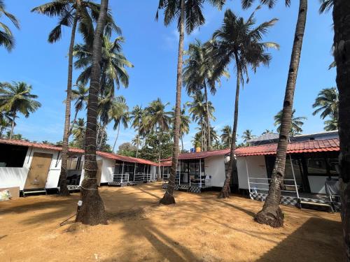 a group of palm trees in front of a building at LAKSHDEEP COTTAGES in Canacona