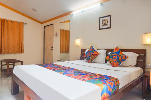 a bedroom with a large white bed with colorful pillows at FabHotel Prime Vishwakirti Agri in Ahmadnagar