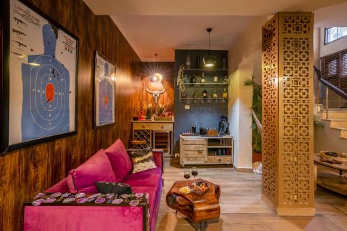 - un salon avec un canapé rose et une table dans l'établissement Alaya Stays Aravali Woods 4BHK Villa with Mini Movie Theatre in Gurgaon, à Gurgaon