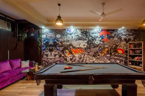 a room with a pool table in front of a mural at Alaya Stays Aravali Woods 4BHK Villa with Mini Movie Theatre in Gurgaon in Gurgaon