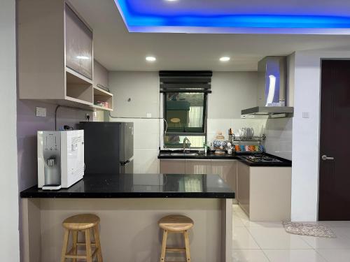 a kitchen with a black counter top and two bar stools at Eijaz Homestay @ Casa Kayangan in Ipoh
