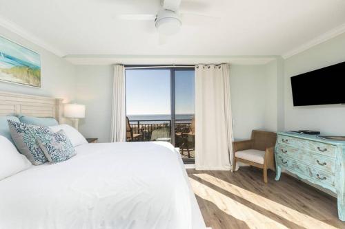 Un dormitorio con una cama blanca y una ventana grande. en Shipwatch 418 - Luxury Oceanfront Penthouse in Isle of Palms, en Isle of Palms