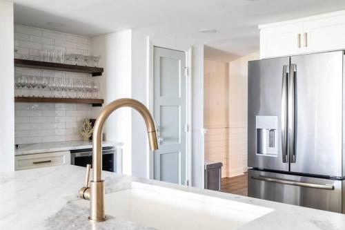 a kitchen with a sink and a stainless steel refrigerator at Shipwatch 418 - Luxury Oceanfront Penthouse in Isle of Palms in Isle of Palms