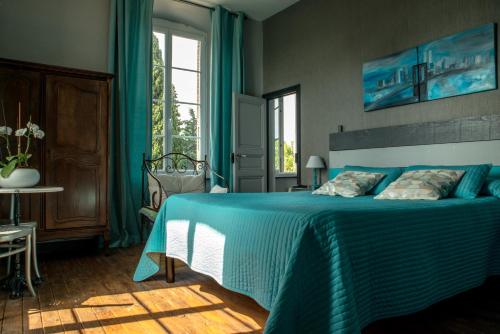 une chambre avec un lit bleu et une fenêtre dans l'établissement Relais de l'Alaric, à Moux