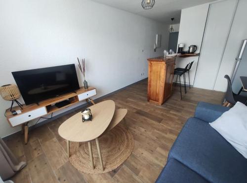 uma sala de estar com um sofá azul e uma mesa em Kaz joli bois studio belle vue em Saint-Denis