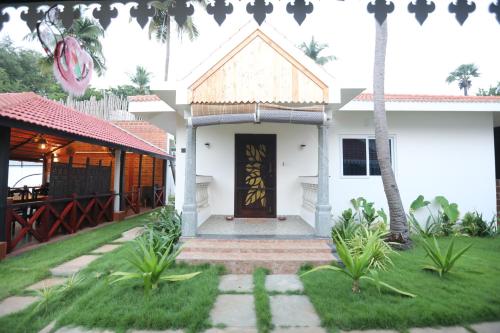 a white house with a door and a grass yard at Athulya Resort -Leisure and Luxury cottages from EMBEHolidays in Kottaikadu