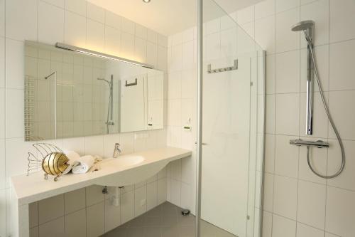 a white bathroom with a sink and a shower at Seevillen Excelsior in Velden am Wörthersee