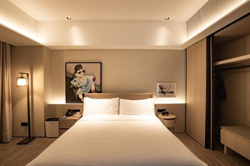 a hotel room with a bed with white sheets at Artyzen Habitat Dongzhimen Beijing in Beijing