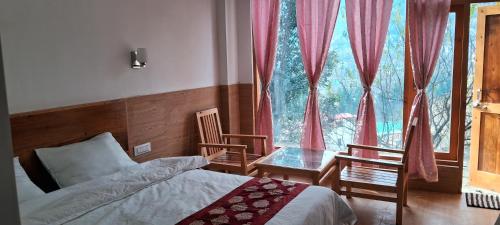 a bedroom with a bed and a large window at JoginiHILLS Premium King Room in Manāli