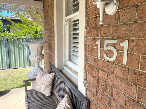 a porch with a bench with a number and a vase at The Edward Townhouse 151 - Tastefully Styled in Orange