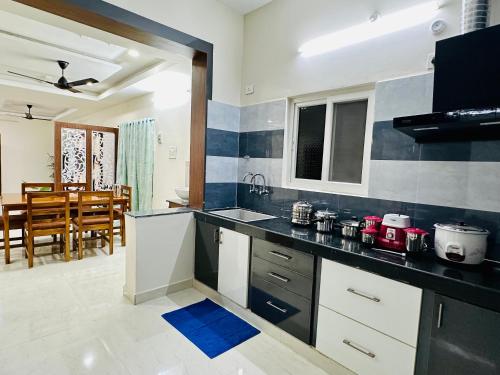a kitchen with a counter and a dining room at TrueLife Majestic Suites - 3BHK Large Signature Apartments - PS4 Veg Restaurant - On the way to Balaji Temple - Modular Kitchen - Large Hall, Super fast WiFi, Smart TV, 250 Jio Channel - Easy access to all Temples - Parking - Top service with lots of Love in Tirupati