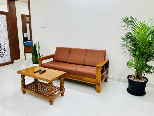a couch and a coffee table in a living room at TrueLife Majestic Suites - 3BHK Large Signature Apartments - PS4 Veg Restaurant - On the way to Balaji Temple - Modular Kitchen - Large Hall, Super fast WiFi, Smart TV, 250 Jio Channel - Easy access to all Temples - Parking - Top service with lots of Love in Tirupati