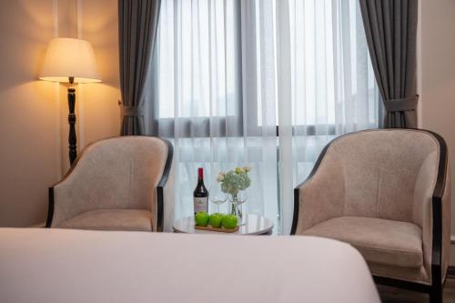 une chambre d'hôtel avec un lit, deux chaises et une table dans l'établissement FTE Ba Dinh Hotel, à Hanoï