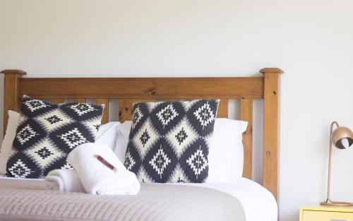 a bed with black and white pillows and a stuffed animal on it at Aston Norwood Chalets in Upper Hutt