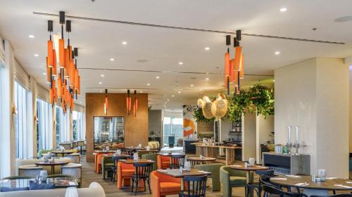 a restaurant with tables and chairs and chandeliers at Almond Hotel - Adults only in Neve Ilan