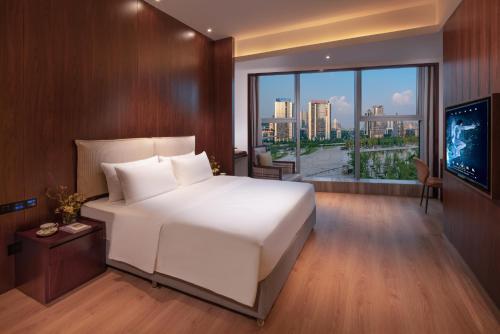 um quarto com uma grande cama branca e uma grande janela em Xunguang Hotel - Chongqing Liangjiang Happiness Plaza em Chongqing