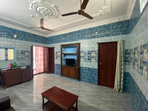 Elle comprend un salon doté de murs carrelés bleus et d'un plafond. dans l'établissement pondy Vibes 2bhk home Stay, à Pondichéry