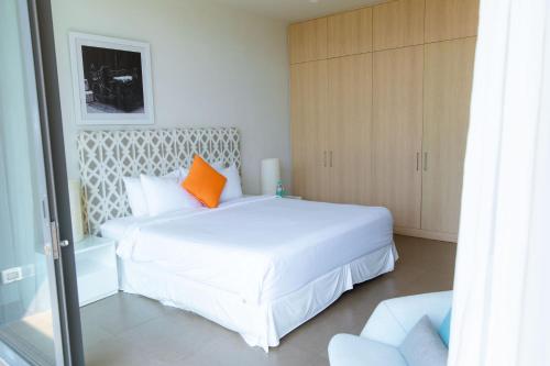 a bedroom with a large white bed with an orange pillow at Beachfront Villa 4 Bedrooms Sanctuary Ho Tram Resort in Thuận Biên