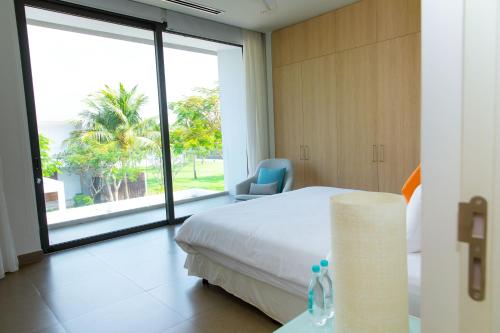 a hotel room with a bed and a large window at Beachfront Villa 4 Bedrooms Sanctuary Ho Tram Resort in Thuận Biên