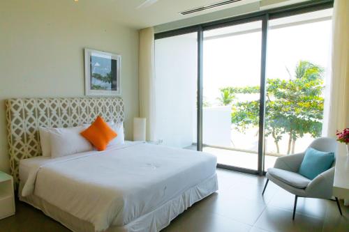 a bedroom with a large bed and a chair at Beachfront Villa 4 Bedrooms Sanctuary Ho Tram Resort in Thuận Biên