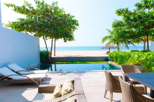 a patio with chairs and a pool and the beach at Beachfront Villa 4 Bedrooms Sanctuary Ho Tram Resort in Thuận Biên