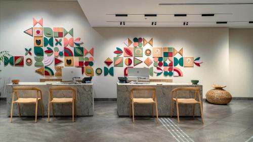 a room with two tables and chairs and paintings on the wall at Almond Hotel - Adults only in Neve Ilan