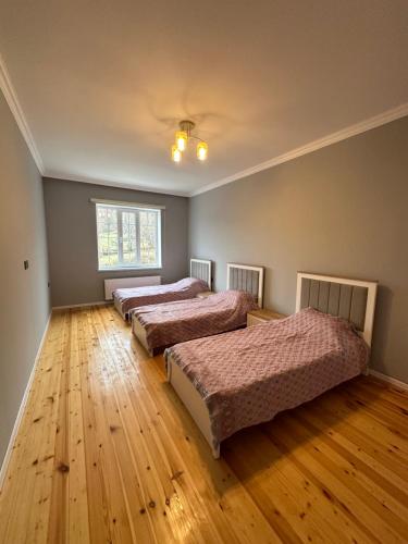 a bedroom with three beds and a wooden floor at JLYN HOUSE in İsmayıllı