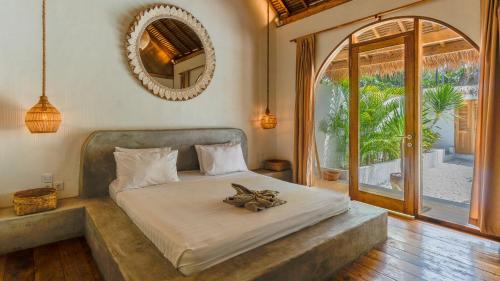 a bedroom with a bed and a large window at Bundi's Villa in Gili Air