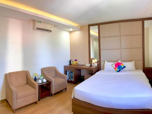 a bedroom with a bed and a desk and a chair at Pariat River Front Hotel in Da Nang