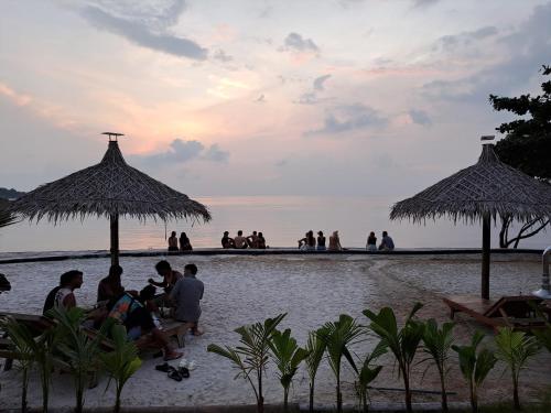 a group of people sitting under umbrellas on the beach at Sense Asia in Haad Tian