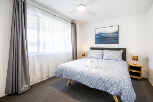 a bedroom with a bed with a stuffed animal on it at The Relax Shack - Pet Friendly - 8 Mins Walk to Beach in Culburra Beach