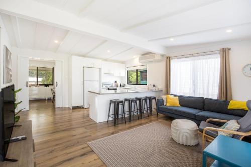 a living room with a couch and a kitchen at The Relax Shack - Pet Friendly - 8 Mins Walk to Beach in Culburra Beach