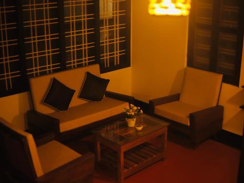 a living room with a couch and two chairs and a table at Paroommel Haven Wayanad in Kenichira