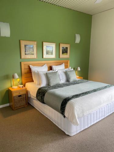 a bedroom with a large bed with green walls at Somewhere Unique in Wollombi