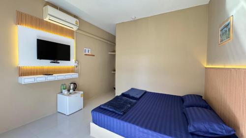 a bedroom with a blue bed and a flat screen tv at มาชิลล์ รีสอร์ท สังขละบุรี in Sangkhla Buri