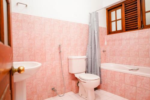 a bathroom with a toilet and a tub and a sink at The Anam Hostel in Colombo