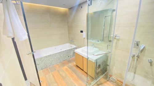 a bathroom with a shower and a sink and a tub at 7 Hills Hotel & Resort in Nalanda