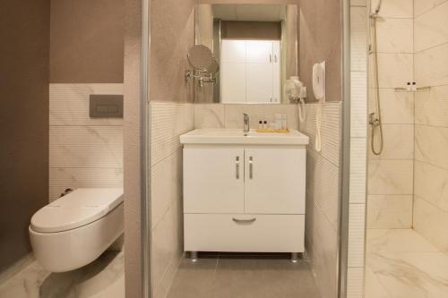 a white bathroom with a toilet and a sink at First Joy Hotel in Trabzon