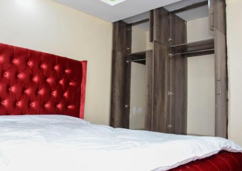 a bed with a red headboard in a room at Madaraka - Nairobi West in Nairobi